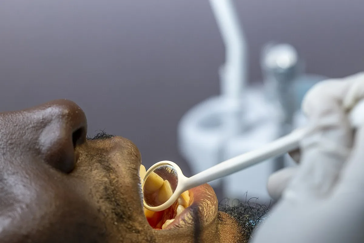 A dentist examining a patient’s teeth with a dental mirror