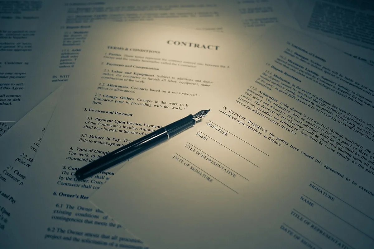 A printed contract document with a fountain pen resting on the signature line