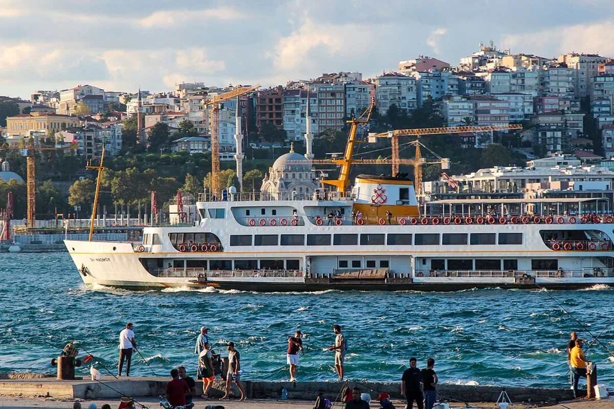 A ferry on the Bosphorus with the Istanbul skyline and a mosque behind it, Turkey